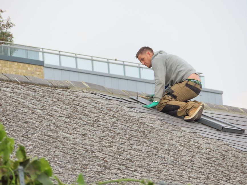 A roofer laying roof covering on a low-pitch roof.