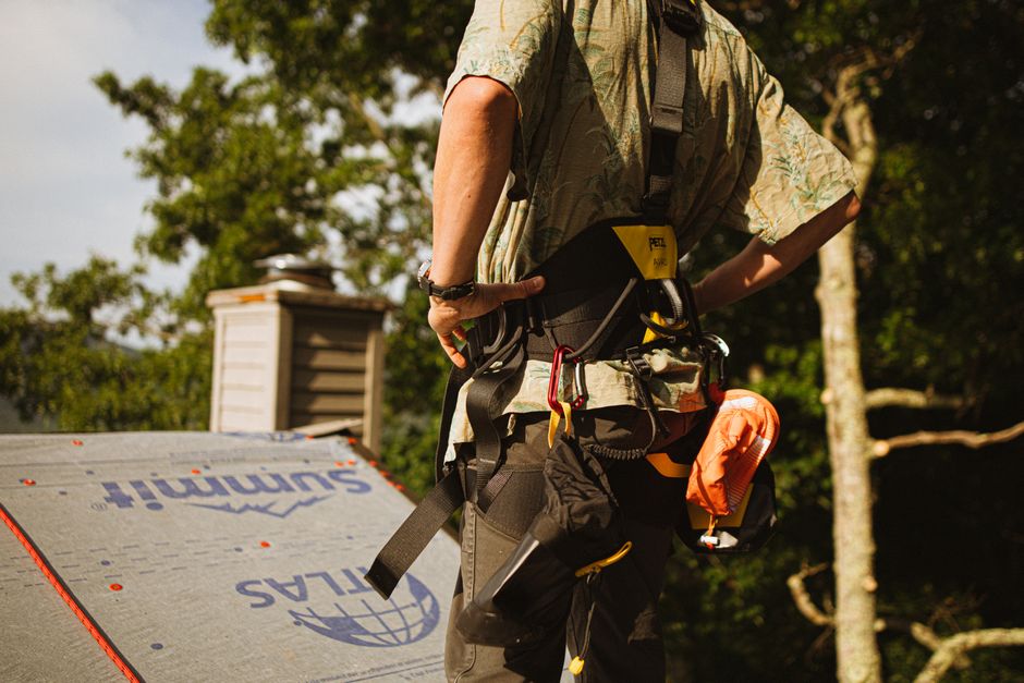 A roofer in a safety harness working on a rooftop.